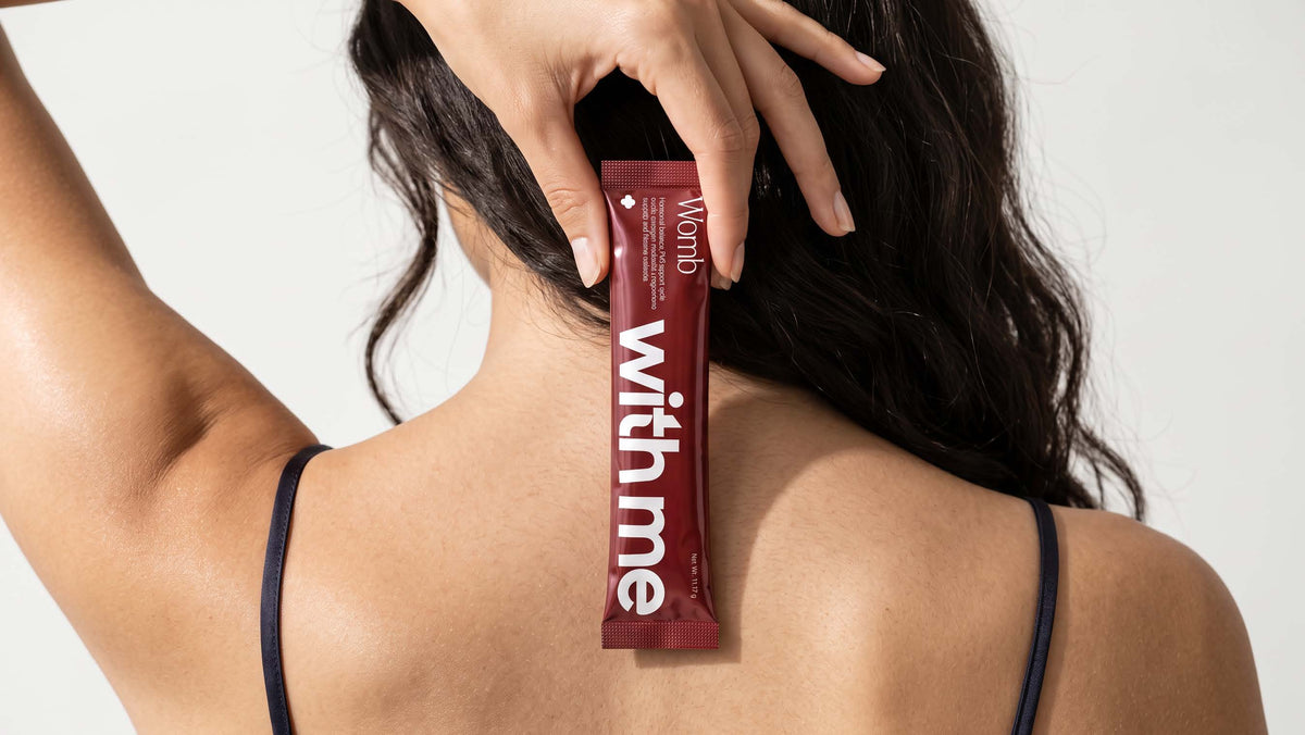 A woman holding the deep red Womb stick pack against the back of her neck
