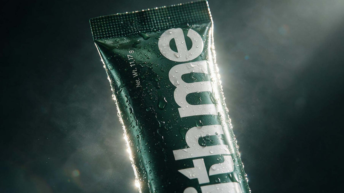 A dark green Guts stick pack covered in water droplets, backlit