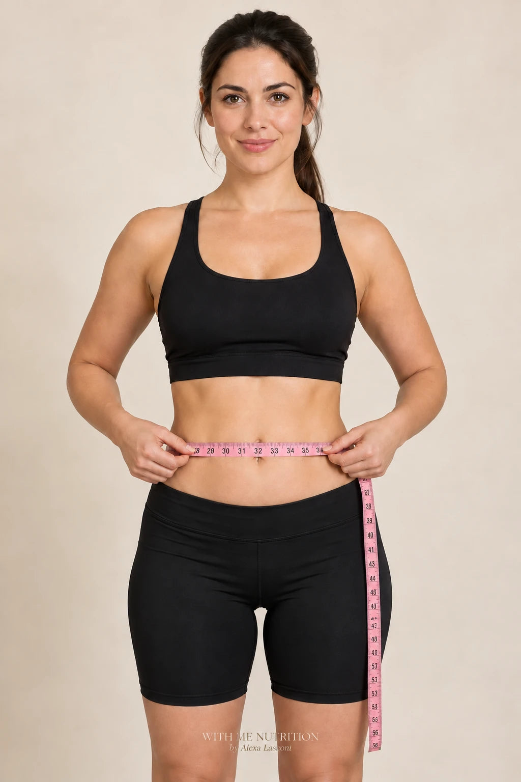 Centimetru de croitorie roz ținut orizontal în jurul abdomenului, la nivelul buricului.